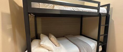Ein Etagenbett mit zwei Schlafstellen, jeweils mit Kissen und Decke.