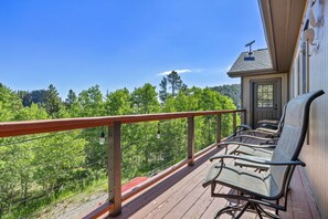 A wooden deck with outdoor seating, overlooking a forested area. - Peak to Peak Retreat | Sleeps 10, Hot Tub, Views (Black Hawk)