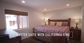 Een masterslaapkamer met een California King bed, een houten hoofdbord, twee nachtkastjes met lampen en een raam met zonwering.