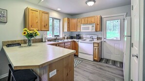 Una cocina moderna con armarios de madera, una estufa blanca y un ventanal grande.