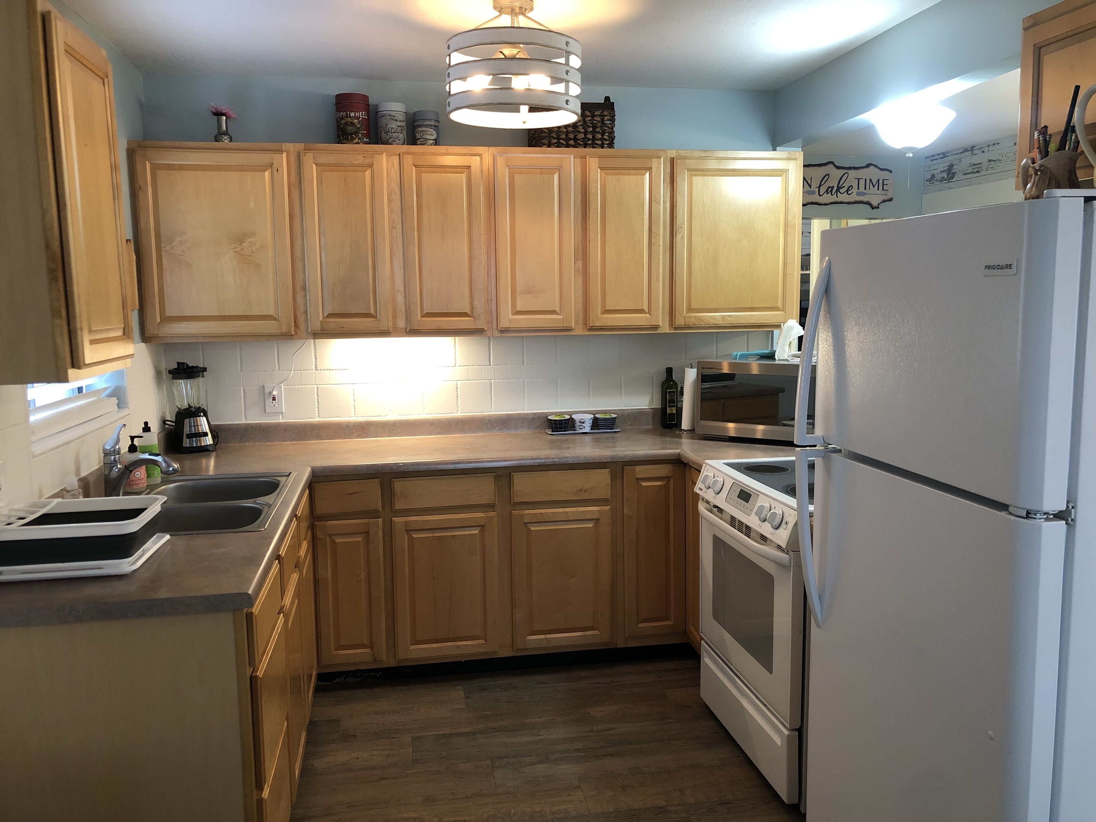 A kitchen with wooden cabinets, a stainless steel refrigerator, a built-in oven, and a countertop with various appliances.