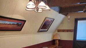 Un espace repas comprenant une table et des chaises en bois, un banc et une lampe fixée au mur.