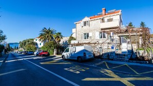 A street with a white van parked on the side, a building with a red roof, and a clear blue sky. - Relaxing Duplex Apartment A3, Close to the Sunset Beach Near Dubrovnik, 2-4 (Dubrovnik)