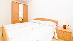 A bedroom with a bed, wooden wardrobe, bedside table, and lamp. - Relaxing Duplex Apartment A3, Close to the Sunset Beach Near Dubrovnik, 2-4 (Dubrovnik)