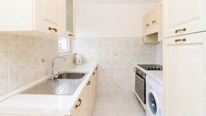 A kitchen with white cabinets, a stainless steel sink, a built-in oven, and a washing machine. - Relaxing Duplex Apartment A3, Close to the Sunset Beach Near Dubrovnik, 2-4 (Dubrovnik)