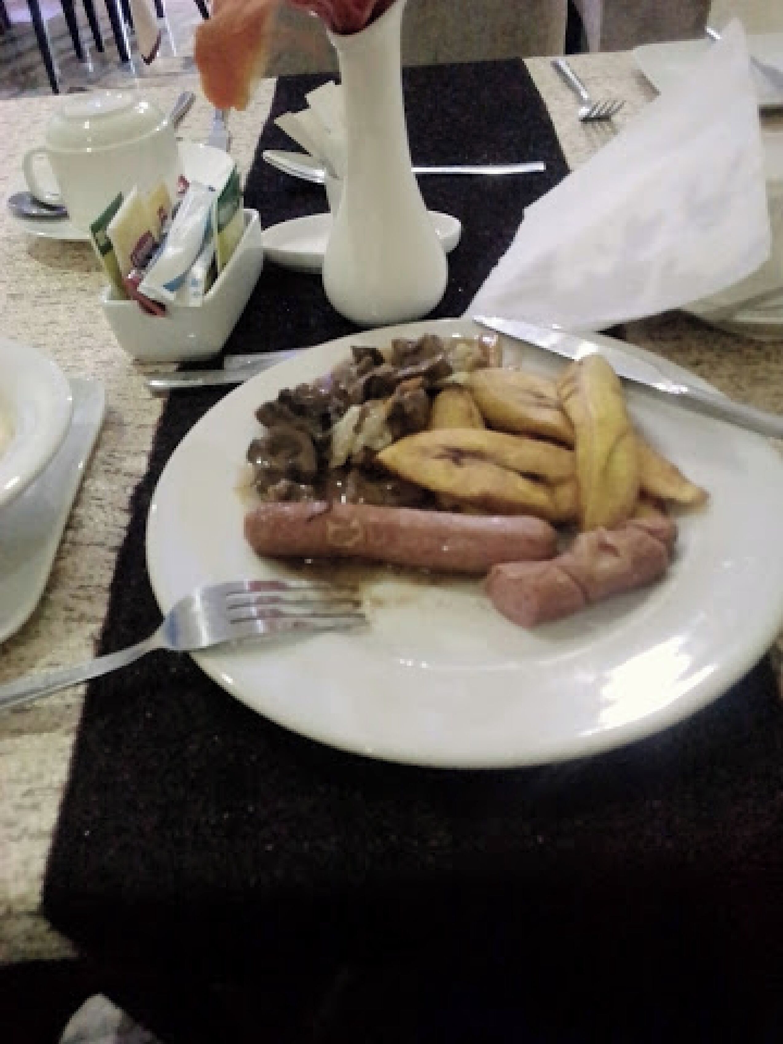 Ein Esstisch mit einer Speisenplatte, einer weißen Vase und einer Tasse.
