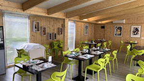 A dining area with wooden walls, green chairs, and tables set for a meal. - Holiday House Sullalbero Rural eco in Alba (Alba)