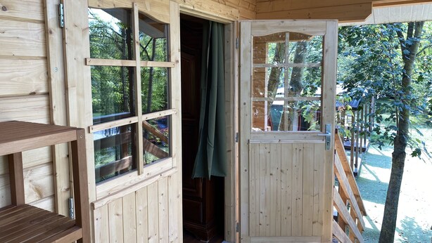 A wooden cabin with a sliding door and windows, a wooden bench, and a view of the surrounding forest. - Holiday House Sullalbero Rural eco in Alba (Alba)
