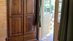 A wooden interior with a large wardrobe, a door leading outside, and a window with curtains. - Holiday House Sullalbero Rural eco in Alba (Alba)