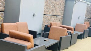 Espace extérieur aménagé avec des chaises et des tables confortables, un mur en briques et une porte en métal.