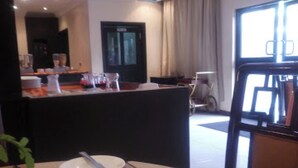Une chambre d’hôtel avec une table à manger dressée pour deux personnes, un téléviseur et une fenêtre avec des rideaux.