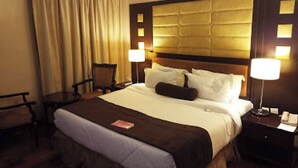 Une chambre d’hôtel avec un grand lit, deux tables de chevet, une chaise et un rideau.