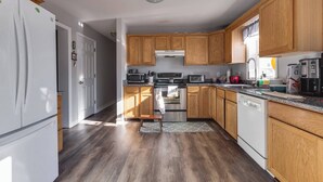 Una cocina con armarios de madera, un refrigerador, un microondas, un horno y un lavavajillas.