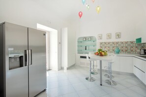 A modern kitchen with a stainless steel refrigerator, a white countertop, and a glass display cabinet.