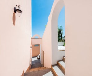 A narrow hallway with a staircase leading to a white bathtub.