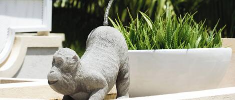A stone sculpture of a monkey in a planter.