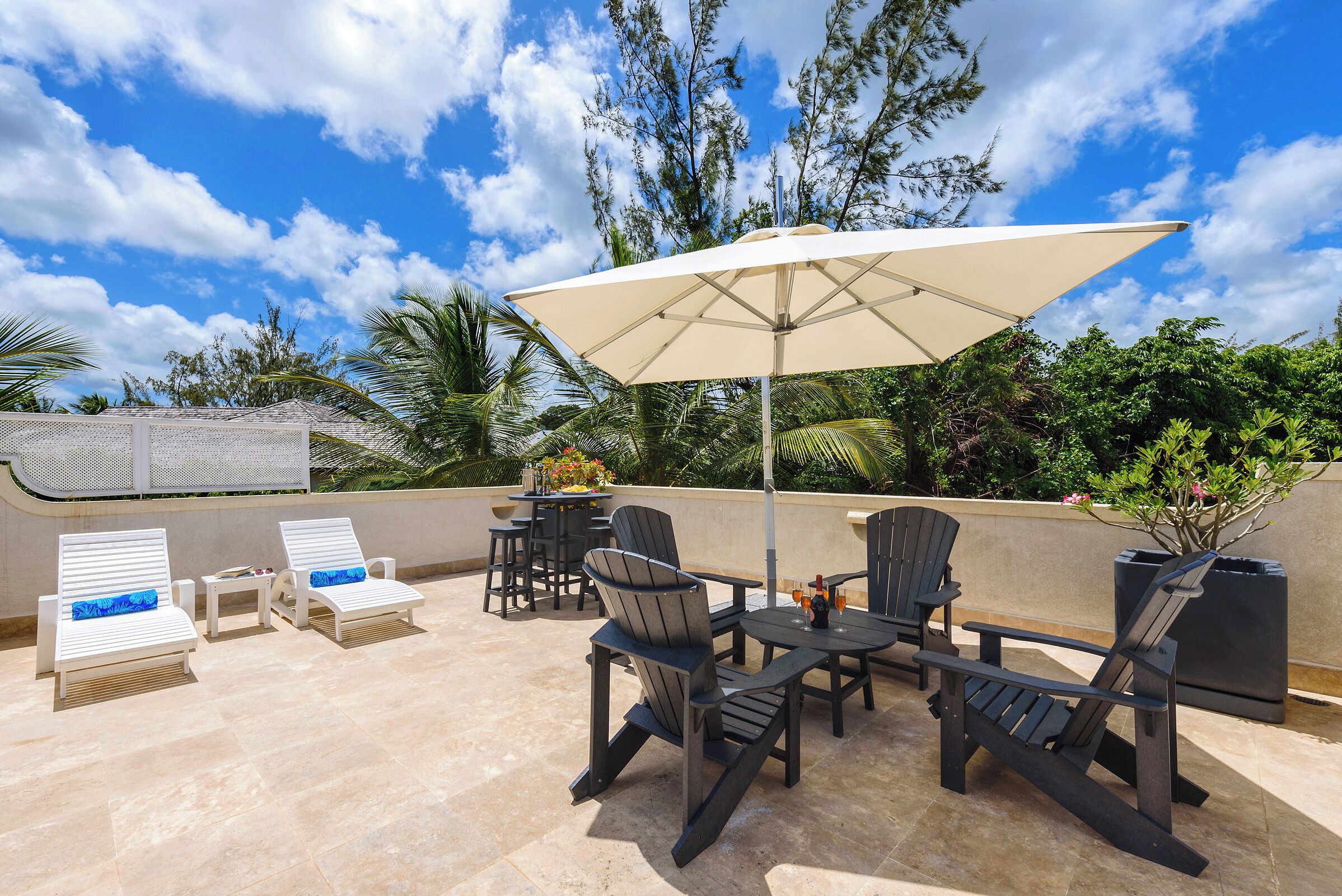Eine Terrasse im Freien mit Lounge-Möbeln, einem Tisch und einem Sonnenschirm.