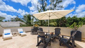 Eine Terrasse im Freien mit Lounge-Möbeln, einem Tisch und einem Sonnenschirm.