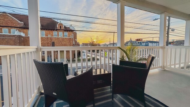 A covered balcony with two wicker chairs and a striped rug. - Wildwood Private ✳ 3BR 2BA APT ✳ 5 min walk to Beach & Boardwalk ★★★★★ Location! (Wildwood)