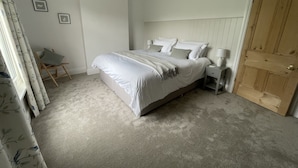 A bedroom with a bed, bedside tables, a chair, and a door. - Castle Cottage in Conwy - 2 minute walk into Conwy yet has delightful garden (Conwy)