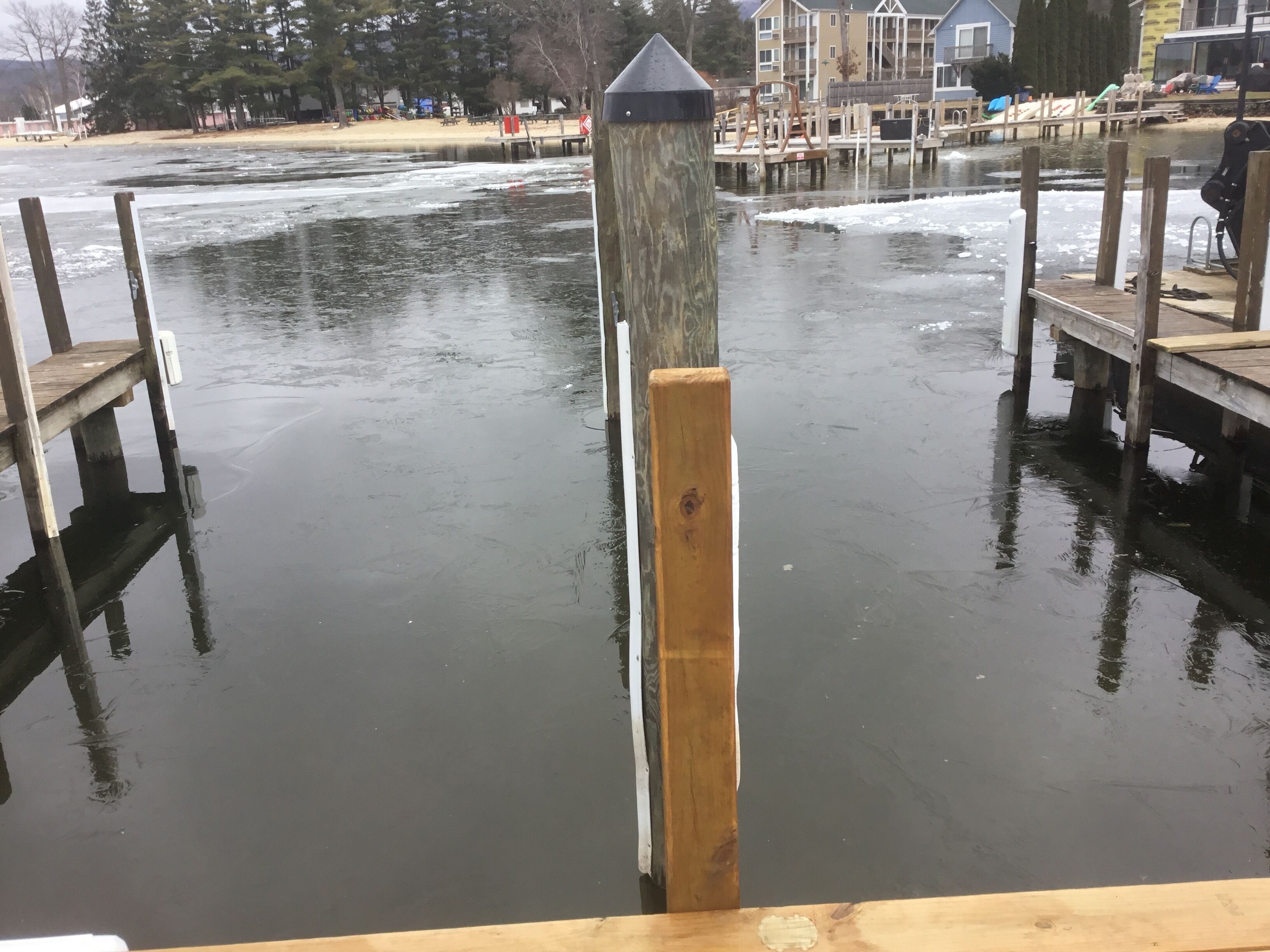 Een houten steiger die uitsteekt in een wateroppervlak, met een aangemeerd bootje en een rij gebouwen op de achtergrond.
