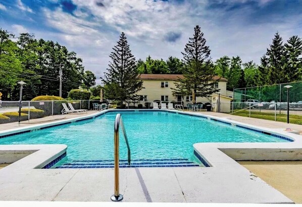A rectangular swimming pool with a metal ladder in the foreground, surrounded by a fence and trees. - 2 BR + Loft Gilford Cottage on Winnipesaukee w/ Deep Water Boat Slip & Beach. (Gilford)