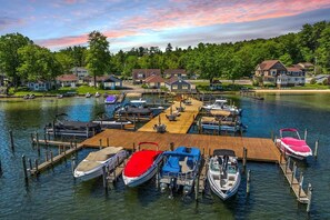A marina with docked boats, a wooden pier, and houses in the background. - 2 BR + Loft Gilford Cottage on Winnipesaukee w/ Deep Water Boat Slip & Beach. (Gilford)