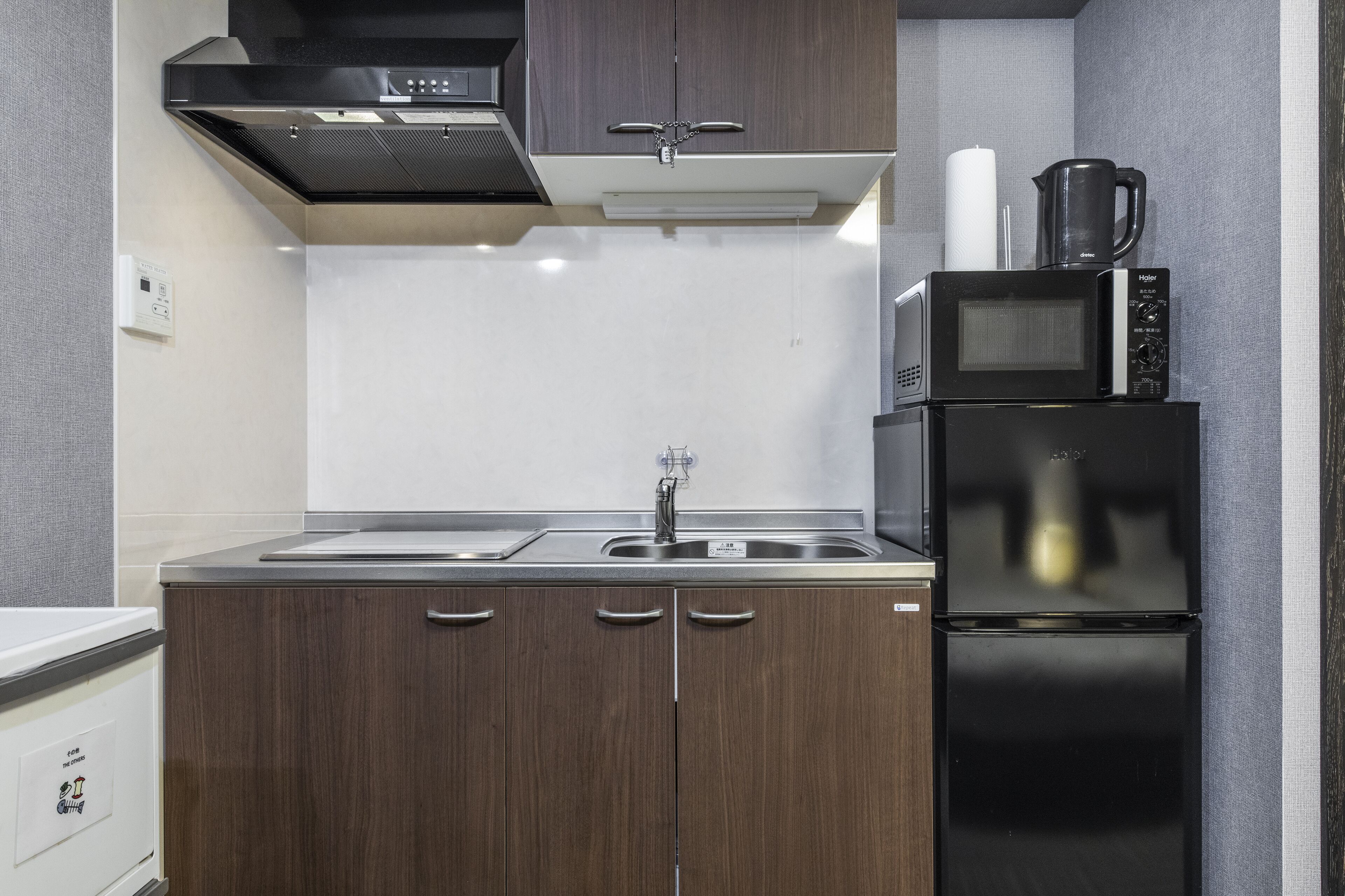 Een compacte keuken met een magnetron, koffiezetapparaat en een koelkast.