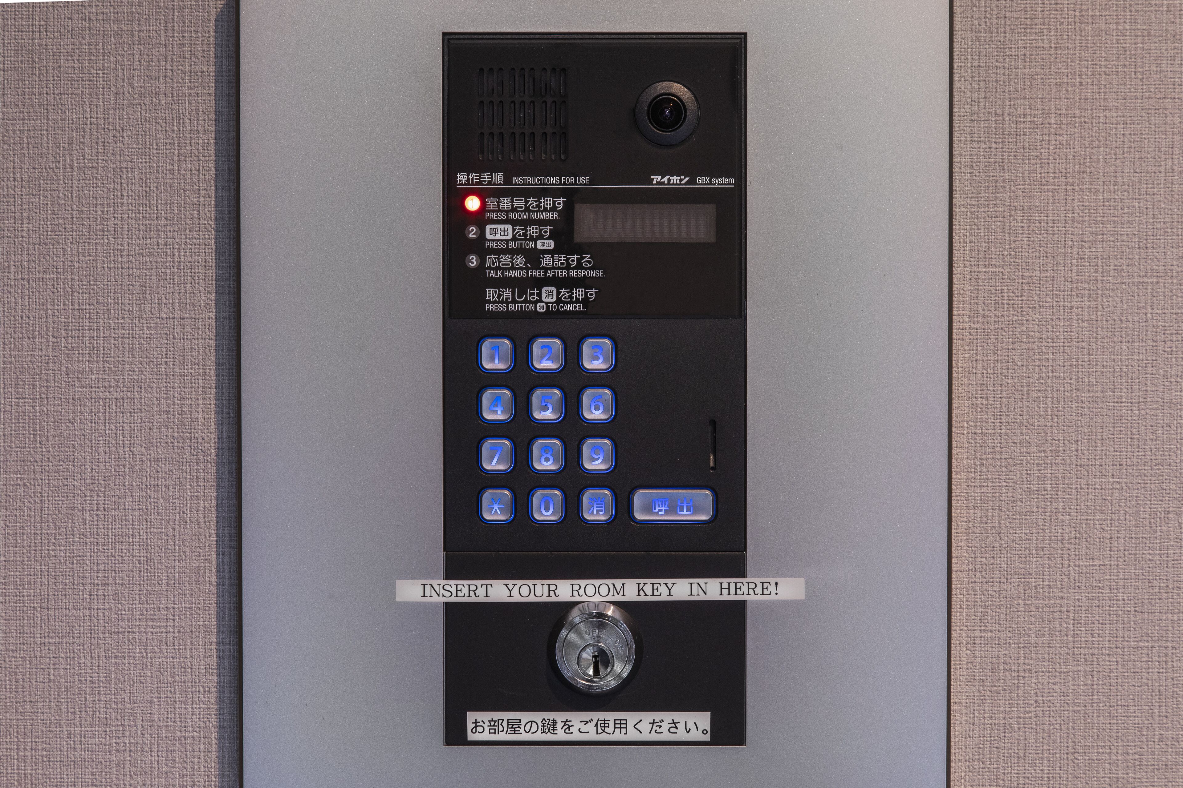 A hotel room's electronic keycard entry system with instructions in multiple languages and a keypad for room number entry.