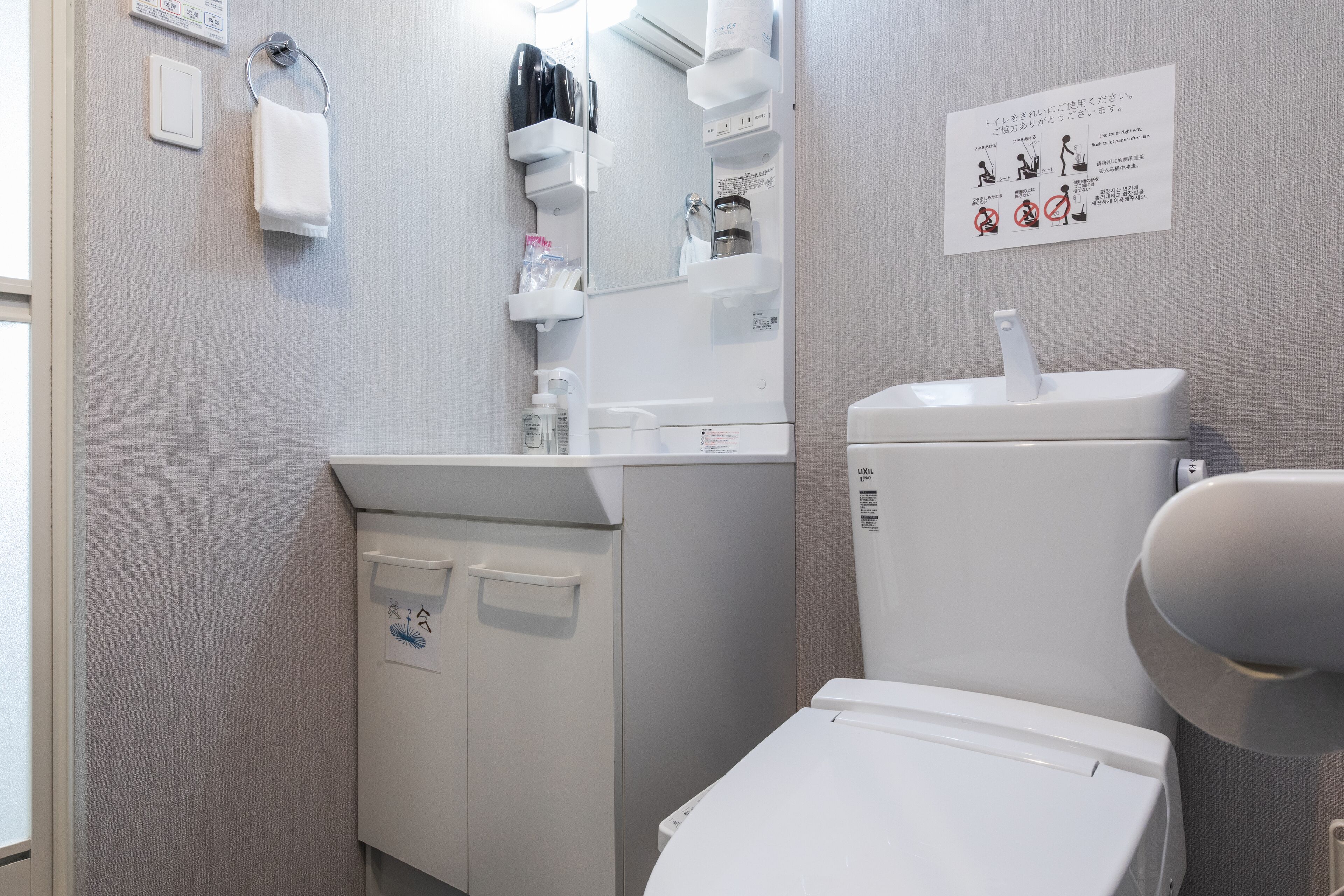 A bathroom with a toilet, sink, and towel rack. There are storage shelves above the sink and a sign with instructions on the wall.