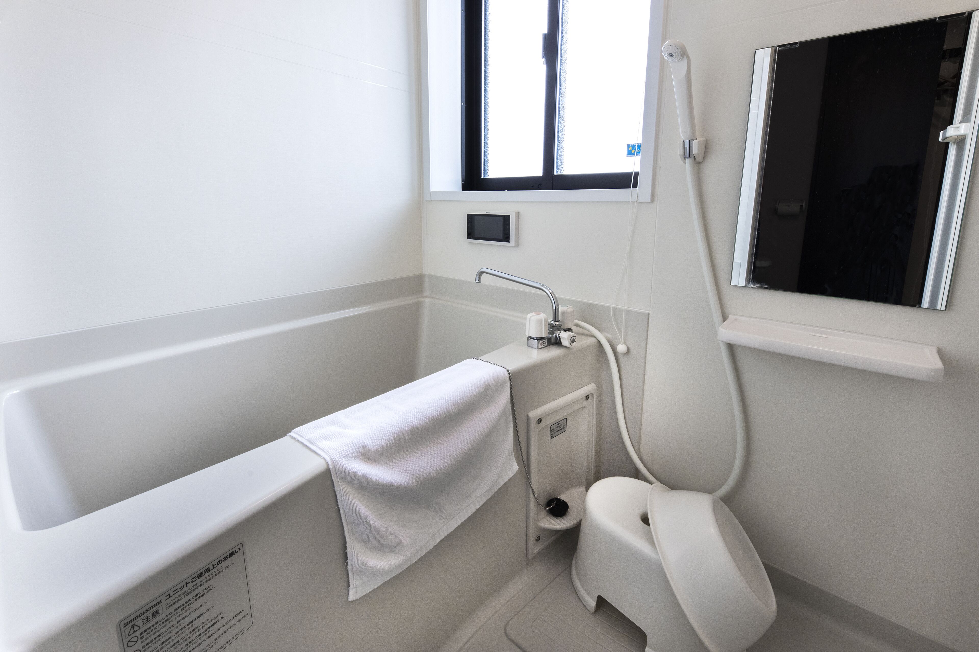 Une salle de bain moderne équipée d’une baignoire, de toilettes et d’une fenêtre laissant entrer la lumière naturelle.