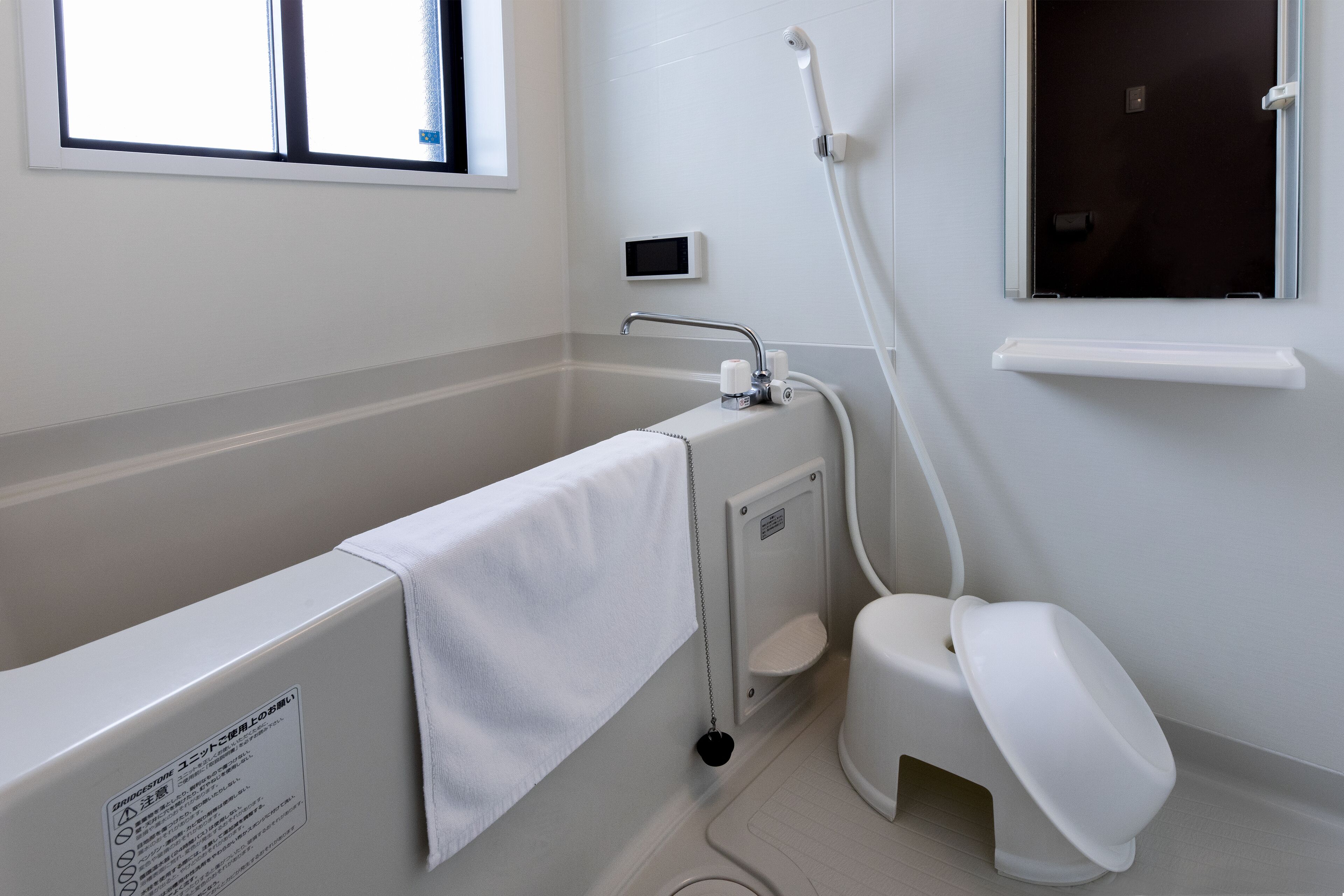 Een moderne badkamer met bad, toilet en een raam dat voor natuurlijk licht zorgt.