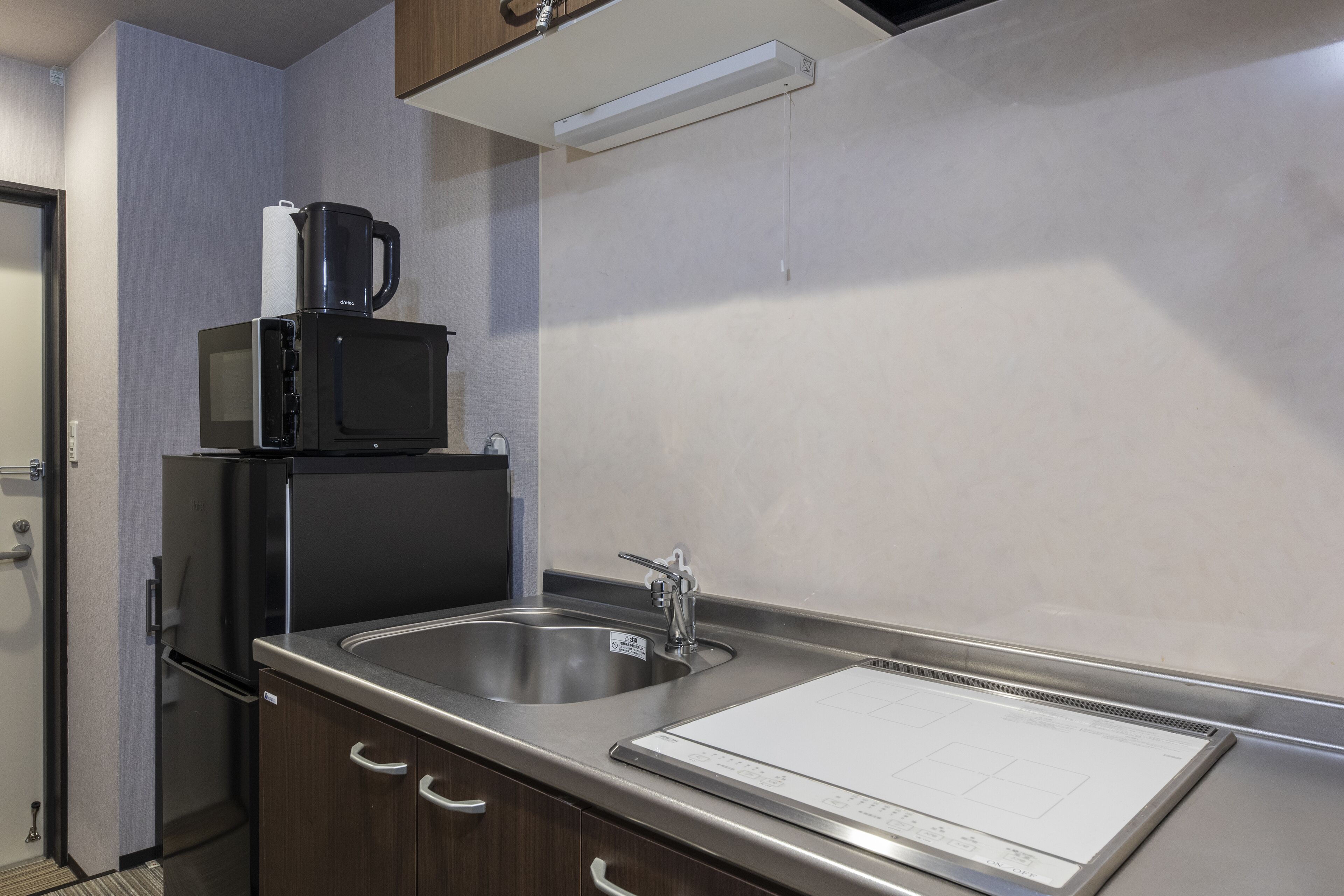 A modern kitchen with stainless steel appliances, a sink, and a countertop with a paper towel dispenser.