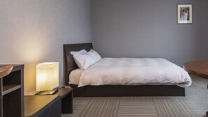 A hotel room with a bed, bedside table, lamp, and a framed picture on the wall. - Tofukuji Riverside (Kyoto)