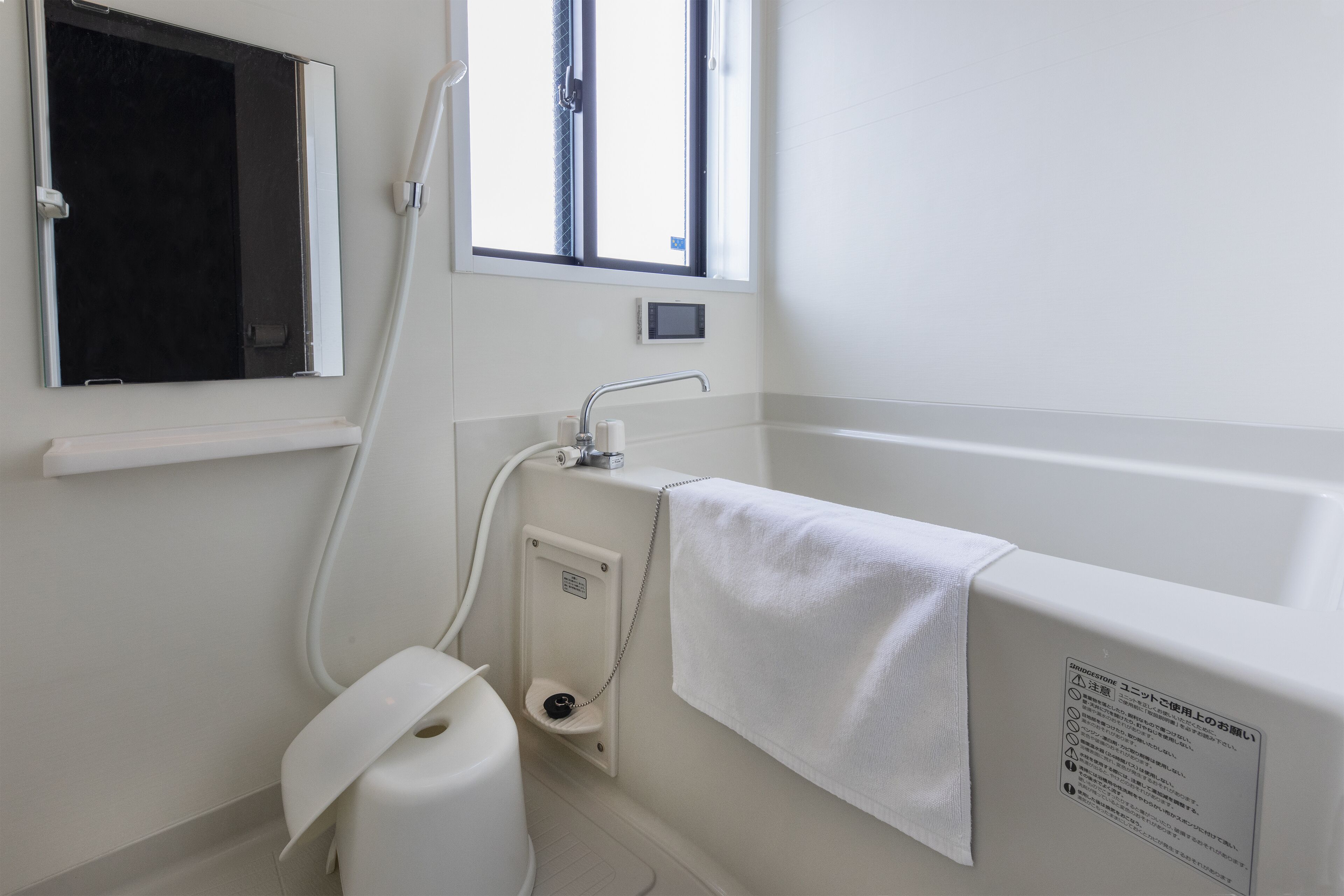Ein Badezimmer mit Badewanne, Toilette, einem Fenster und einem Handtuch an der Wand.