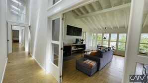 Amplia sala de estar con un ventanal grande, un sofá, un televisor y un escritorio de madera.