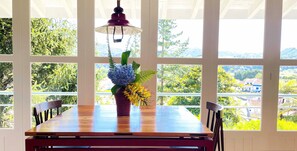 A dining table with chairs, a vase with flowers, and a hanging light fixture. - Casa de Férias Familiar (Furnas)