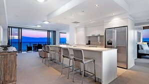 Uma cozinha moderna com uma ilha grande, banquetas e vista para o oceano.