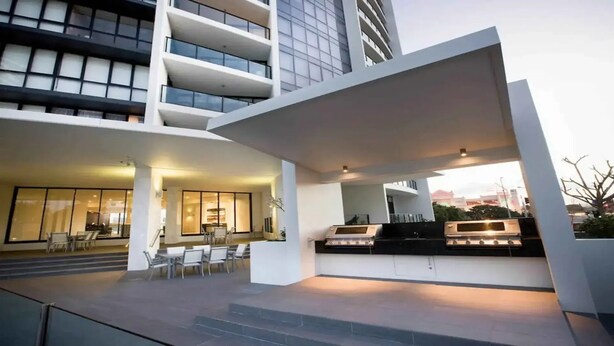 A modern building with a rooftop bar, outdoor seating, and a staircase leading to the entrance. - Hinterland Views 2BR apartment - Sierra Grand - CoastHM (Broadbeach)