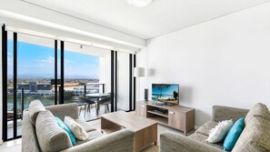 Enjoy a panoramic city view from the comfort of this spacious living room, featuring a sofa, armchairs, and a flat-screen TV.