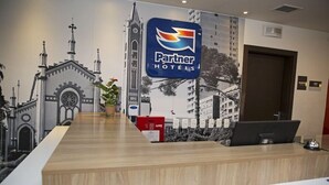 Un mostrador de recepción de hotel con un gran letrero que dice 'Partner Hotels', una computadora y un extintor rojo.