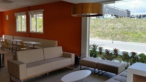 Un interior moderno con sofá, reposapiés y comedor.