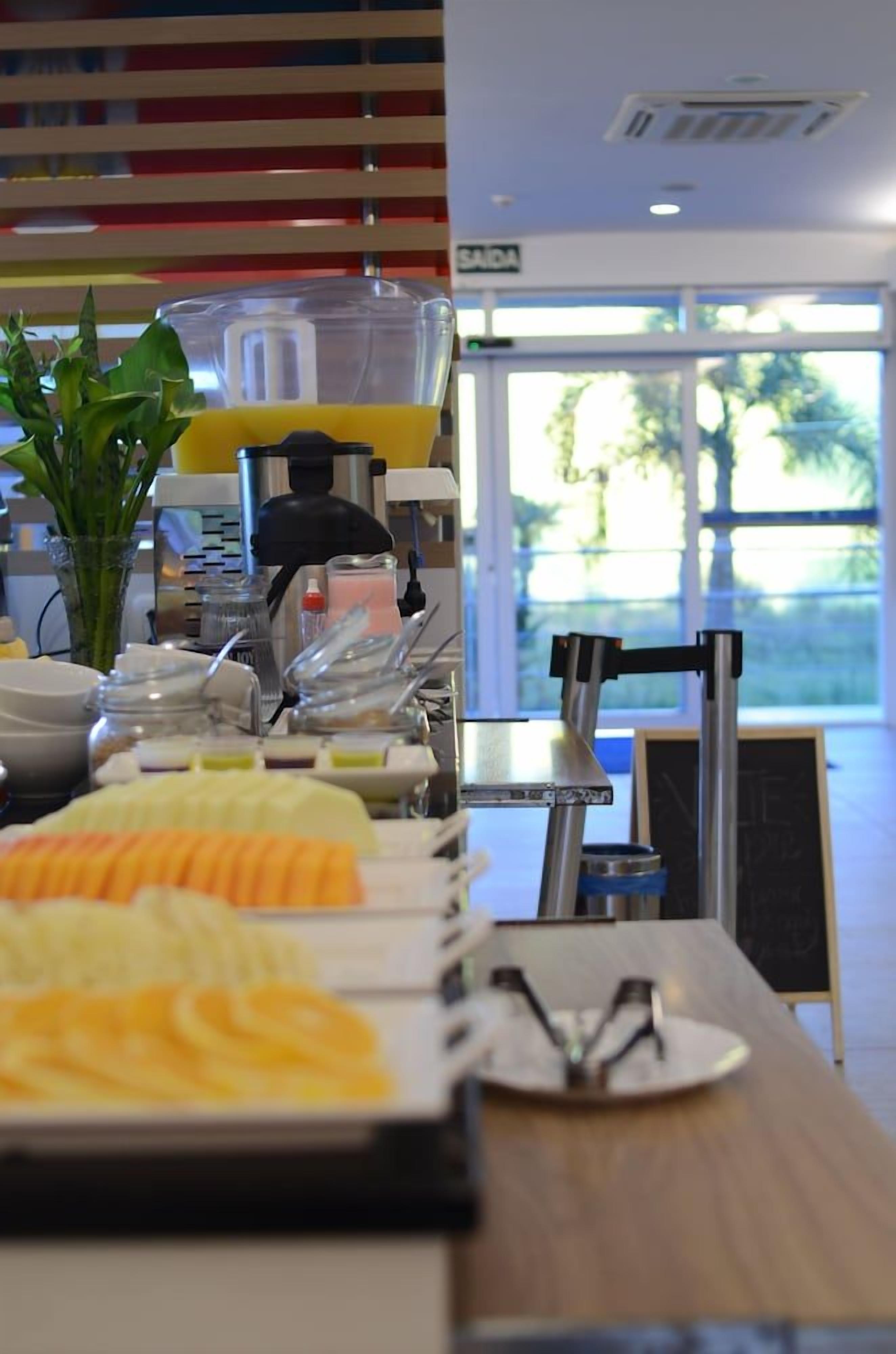 Disposição de buffet com diversos alimentos e um dispensador de sucos.