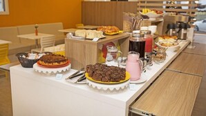 Un bufé con diversos alimentos y bebidas, que incluye un pastel, pastelería y una estación de café.