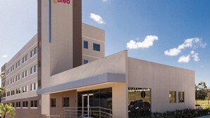 Un moderno edificio de hotel con un llamativo letrero 'Oleo', varios pisos y una zona de entrada cubierta.