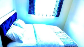 A bed with a blue headboard, white bedding, and a patterned blanket.