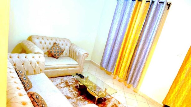 A living room with a sofa, a glass coffee table, and a patterned rug.