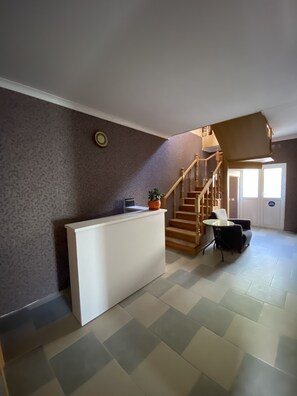 Relax in a spacious interior with a reception desk, staircase, and seating area.