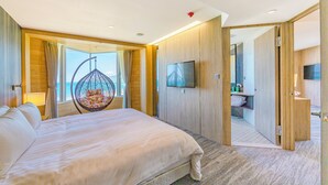 A modern hotel room with a large bed, a hanging chair, a TV, and a view of the ocean. - Kenting Long Beach Hotel (Checheng)