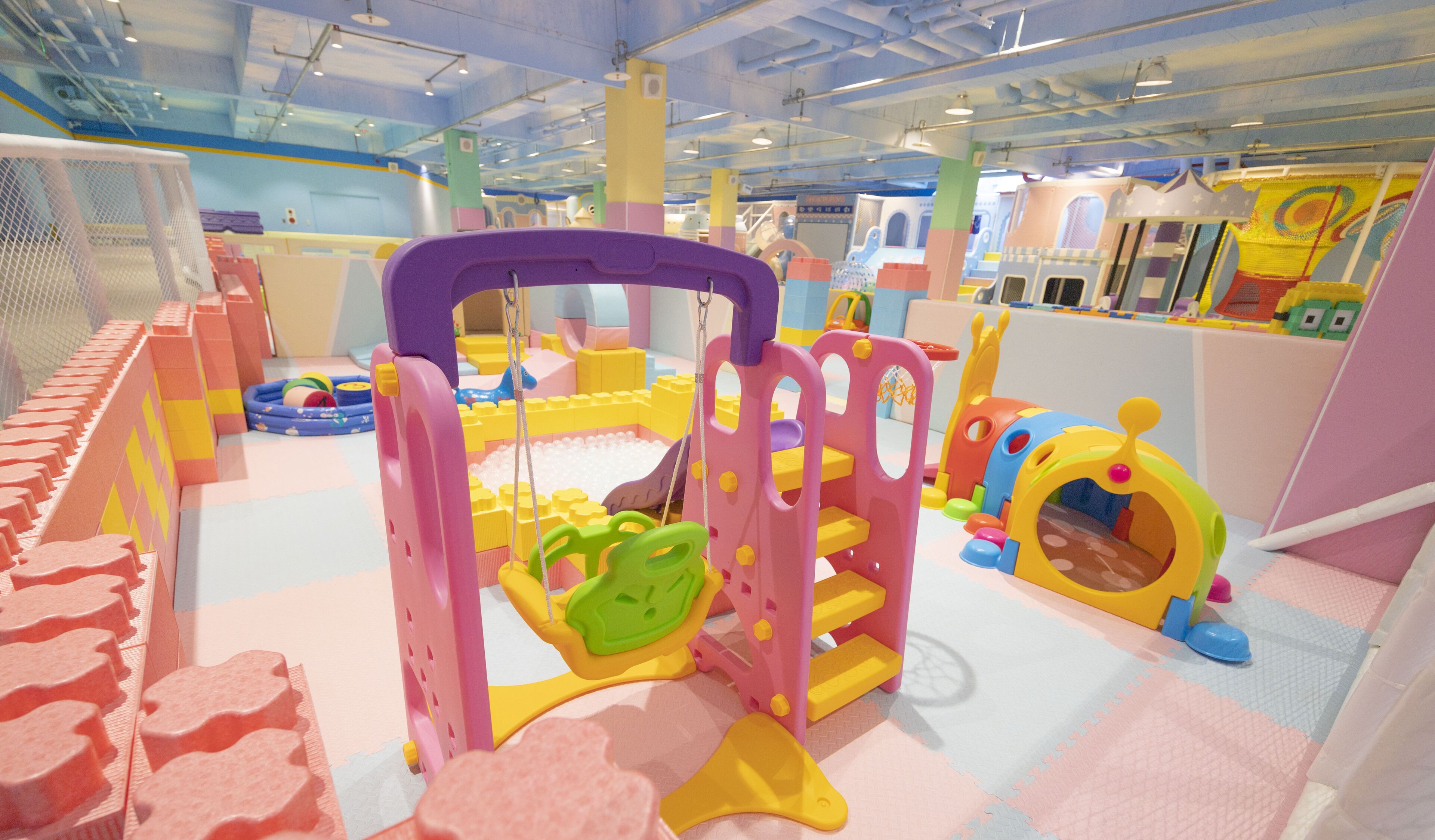 Zona de juegos infantiles con diversas estructuras coloridas y suelo acolchado.